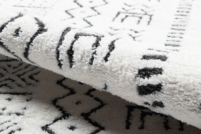 Plush white shag rug with black geometric tribal pattern; soft pile, rolled edge, modern living room decor.