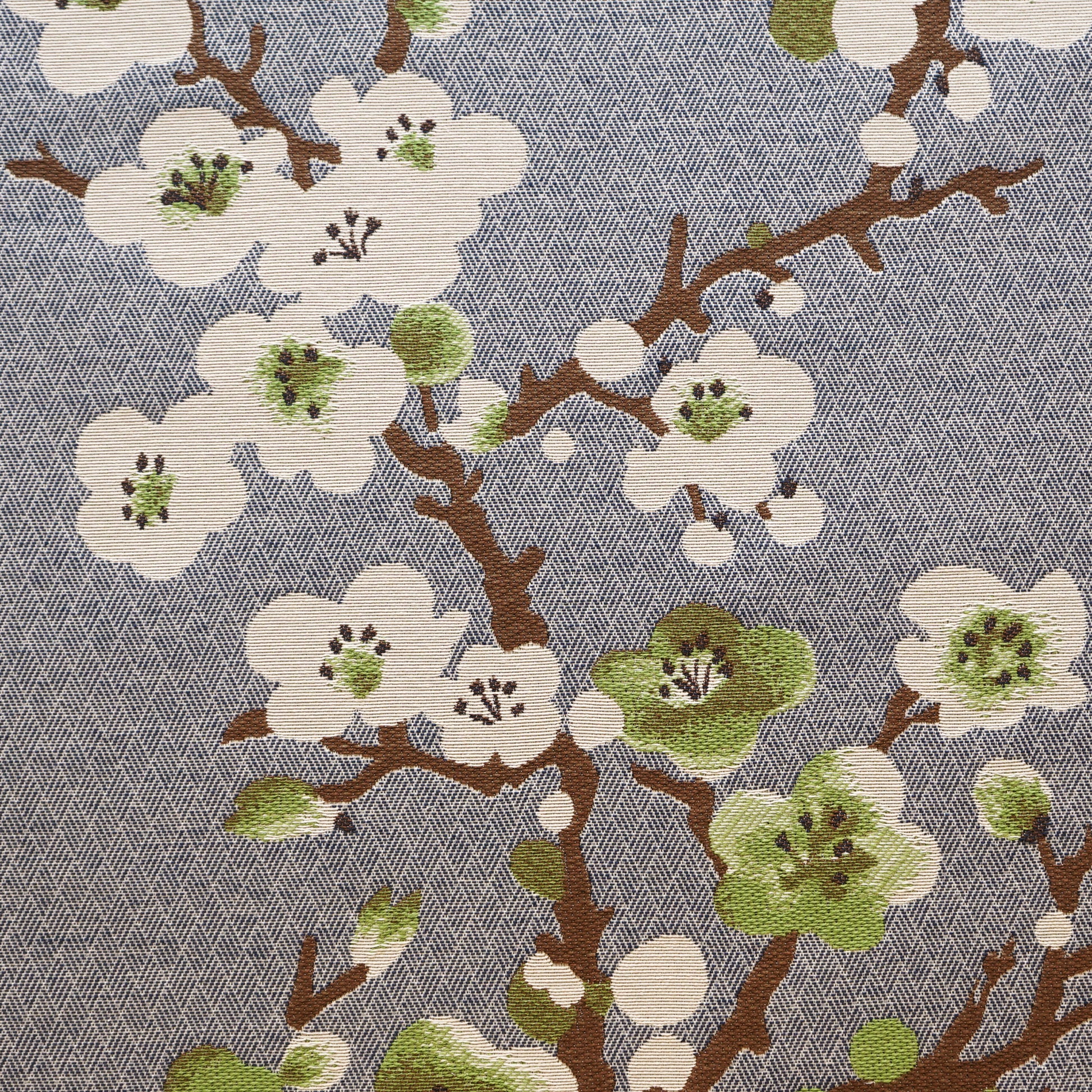 Blue textured fabric with white cherry blossoms, green centers and brown branches; botanical print for upholstery or apparel.