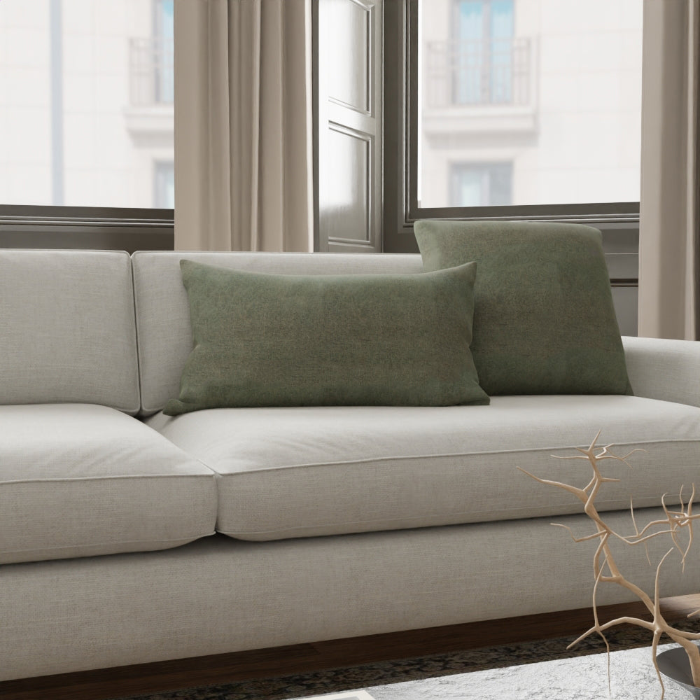 Beige fabric sofa with olive-green cushions in a bright living room, window view and minimalist twig decor.