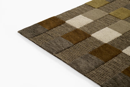 Patchwork rug with brown, tan, beige & gray squares in striped textures, angled corner view.