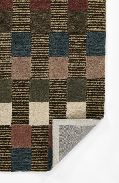 Geometric woven rug with a checkerboard of brown, tan, olive and slate blue; folded corner reveals grey backing.