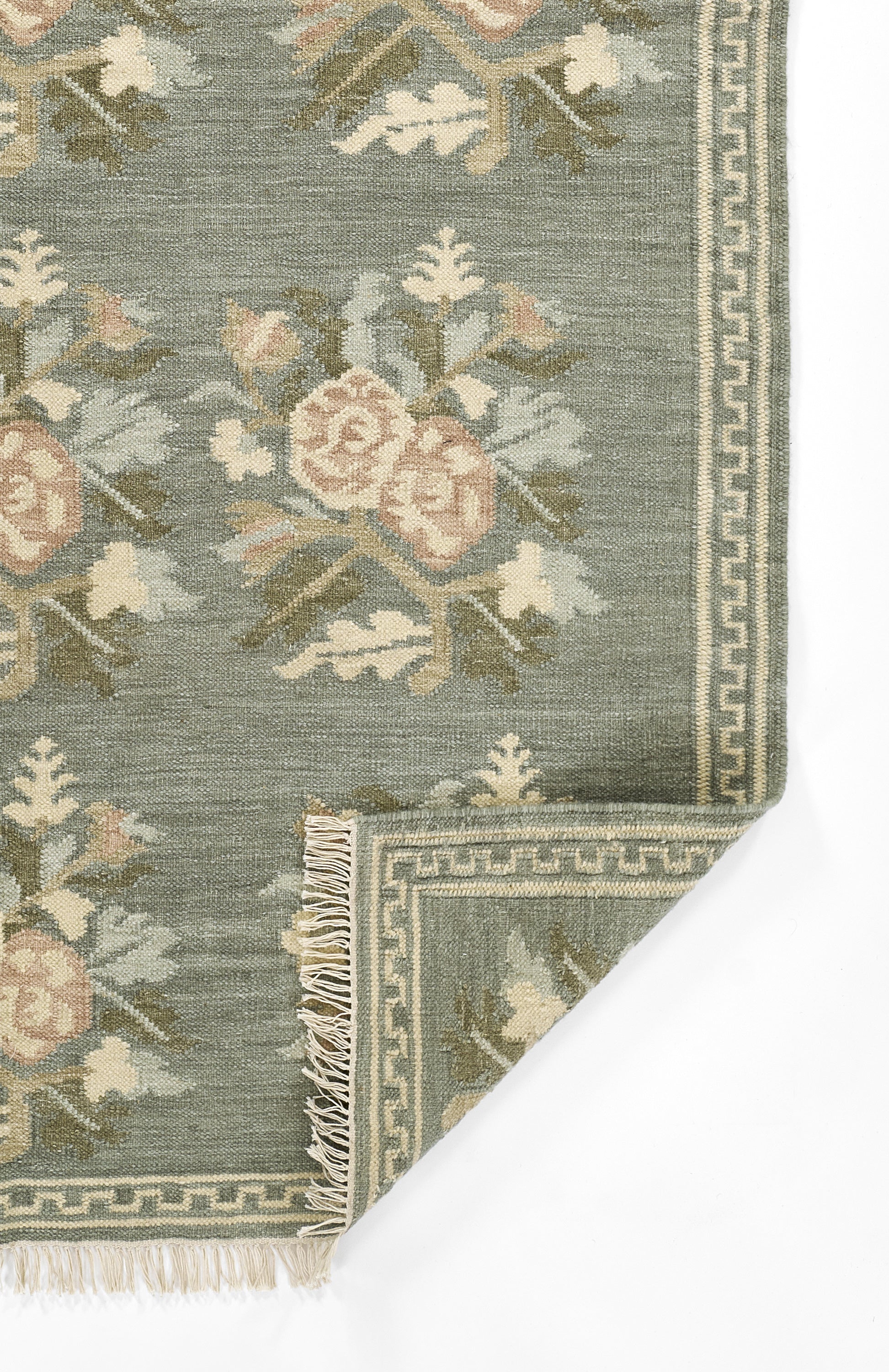 Blue-green floral rug with ivory-pink blossoms, framed by Greek-key border and fringe.