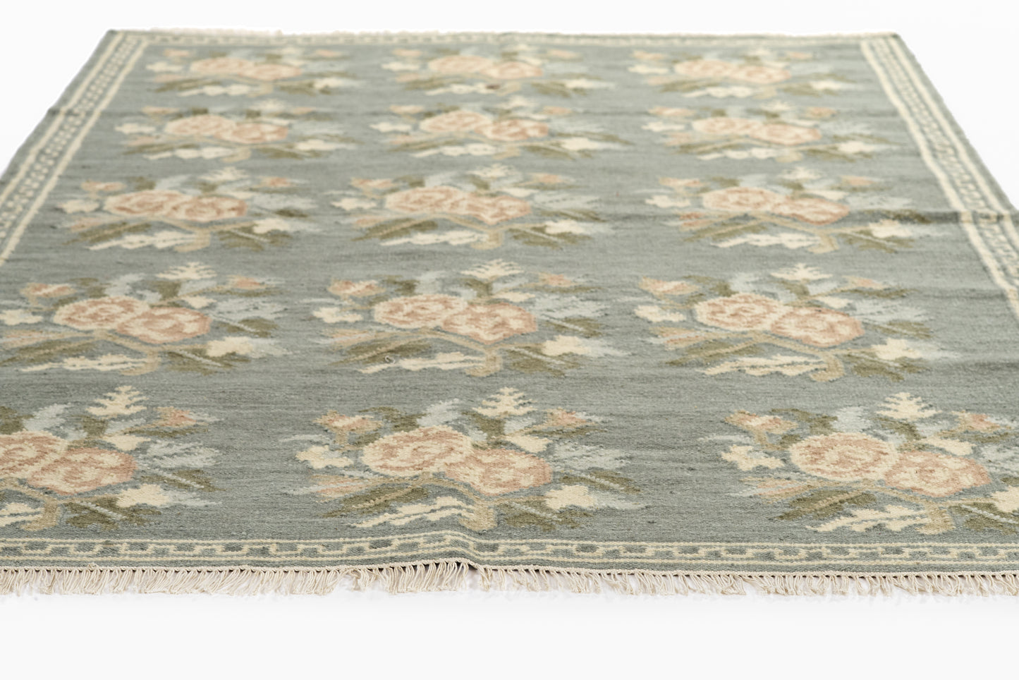 Blue-gray floral area rug with cream-pink roses, fringed ivory edge, oriental-style border.