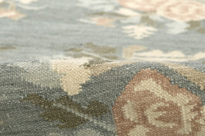 Close-up of a blue floral woven rug with beige and brown accents, tapestry-style texture.