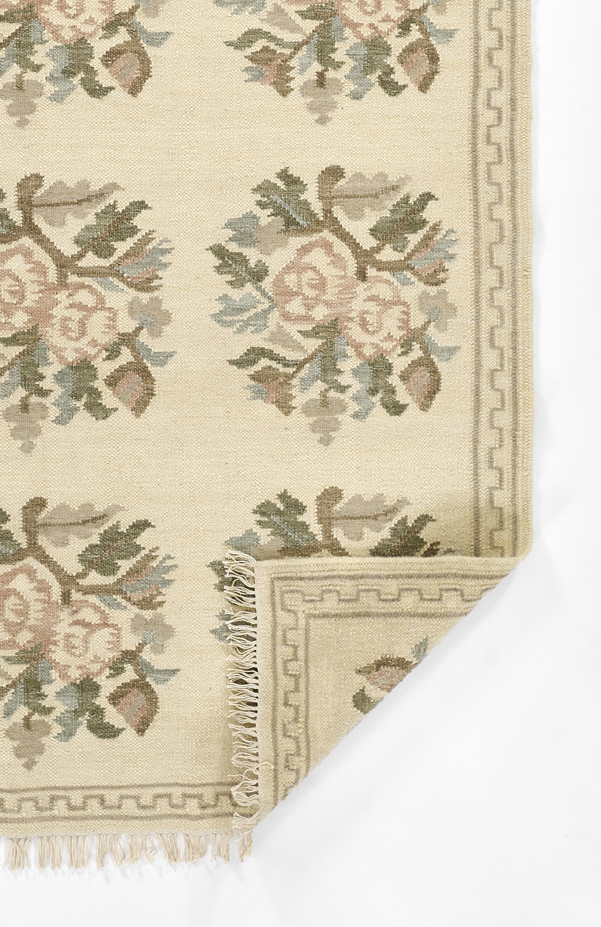 Beige floral area rug with pastel pink blooms & green ivy, geometric border & fringe edges.