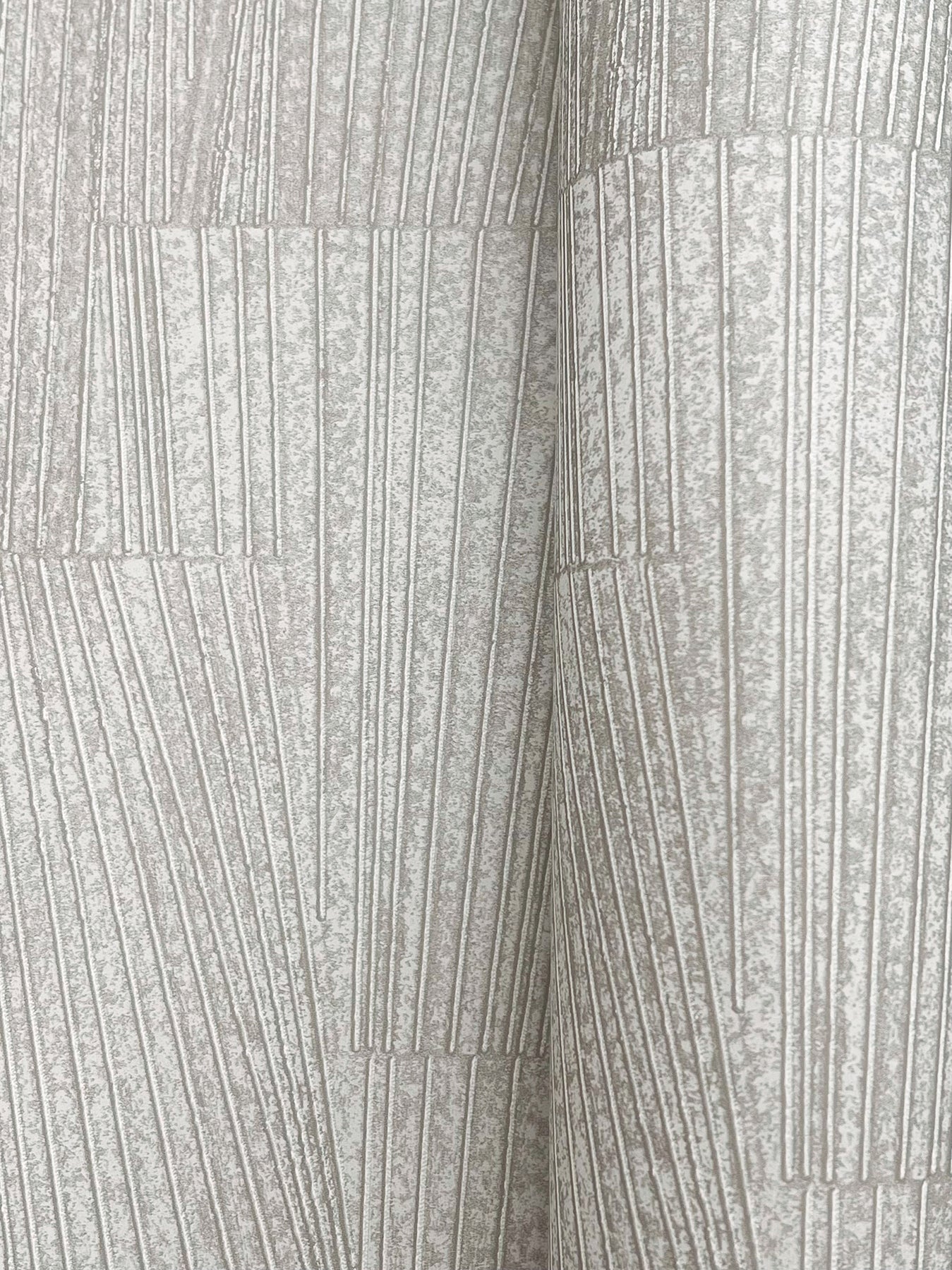 Close-up of stone-grey wallpaper with a geometric pattern and metallic sheen.