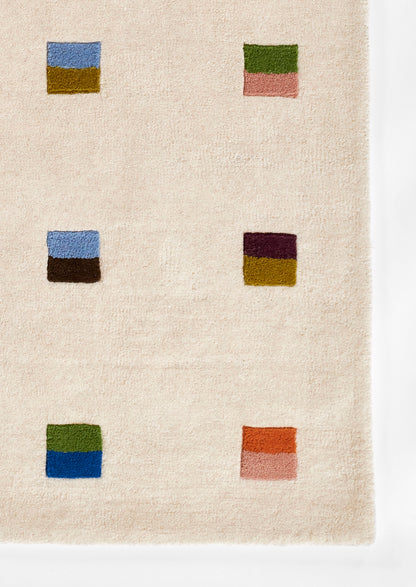 Beige rug with six square color blocks in blue/mustard, green/pink, blue/brown, burgundy/olive, olive/blue, and orange/pink.