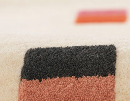 Close-up of a textured beige rug featuring black and rust-brown color blocks.