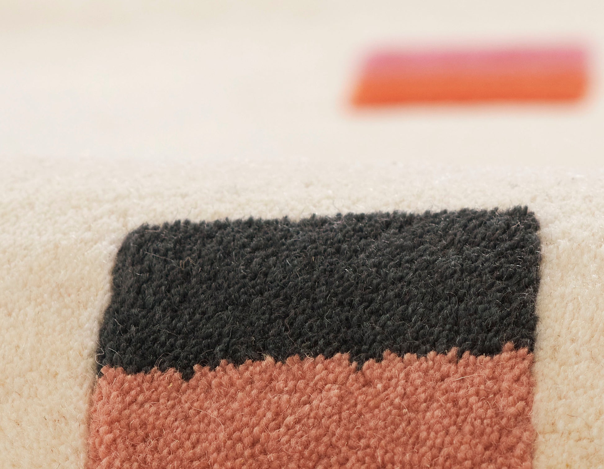 Close-up of a beige runner rug with black and terracotta rectangular color blocks in a two-tone plush pile.