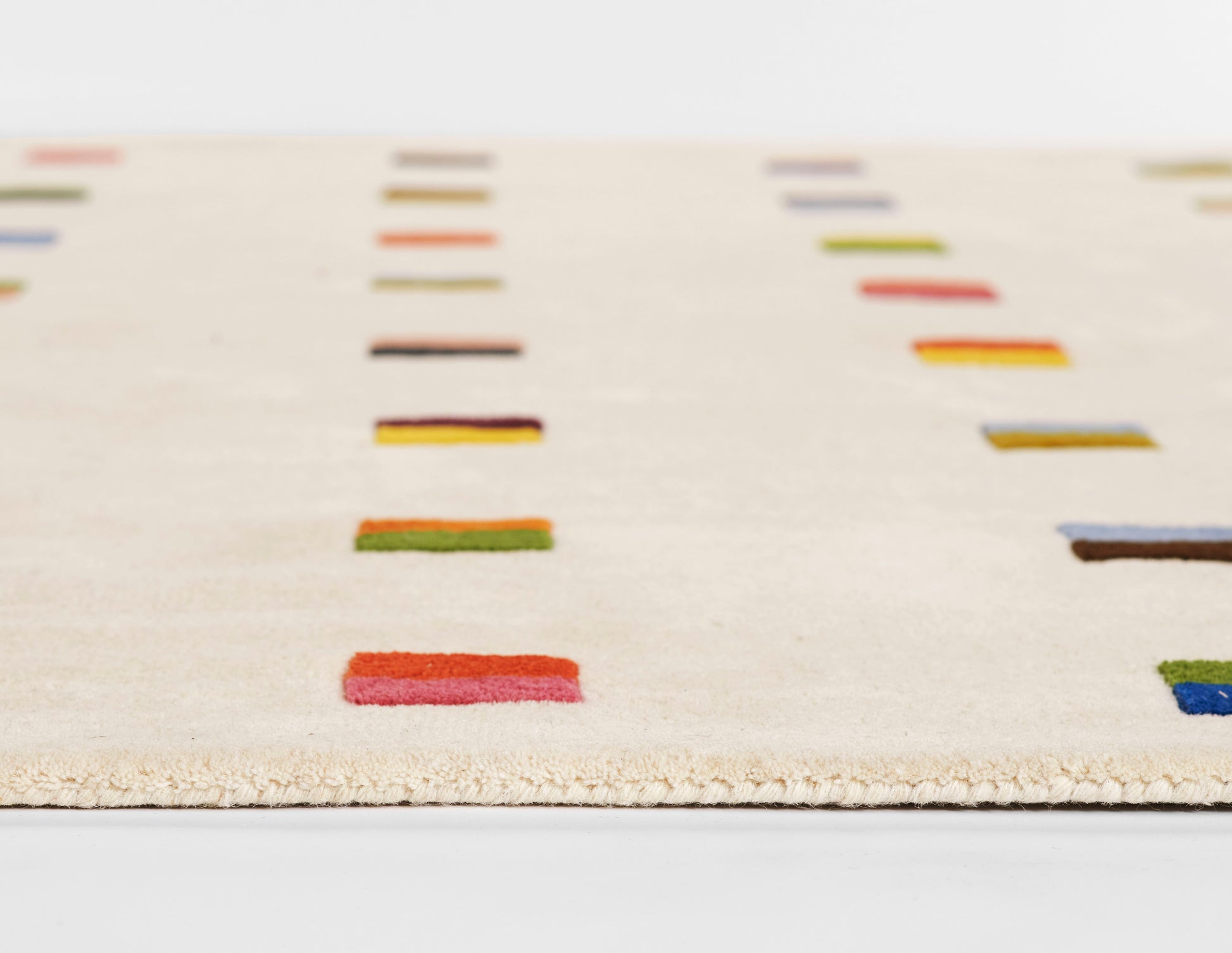 Beige flat-weave runner rug with scattered multicolor rectangular blocks in red, green, blue and orange; modern, playful decor.