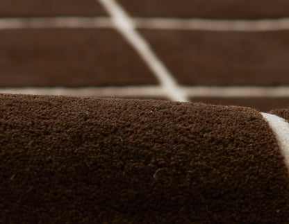 Close-up of dark brown carpet tiles with white seams, textured loop-pile surface, modular flooring.