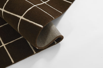 Brown grid-pattern rug, partially rolled to reveal grey underside, cozy floor decor.