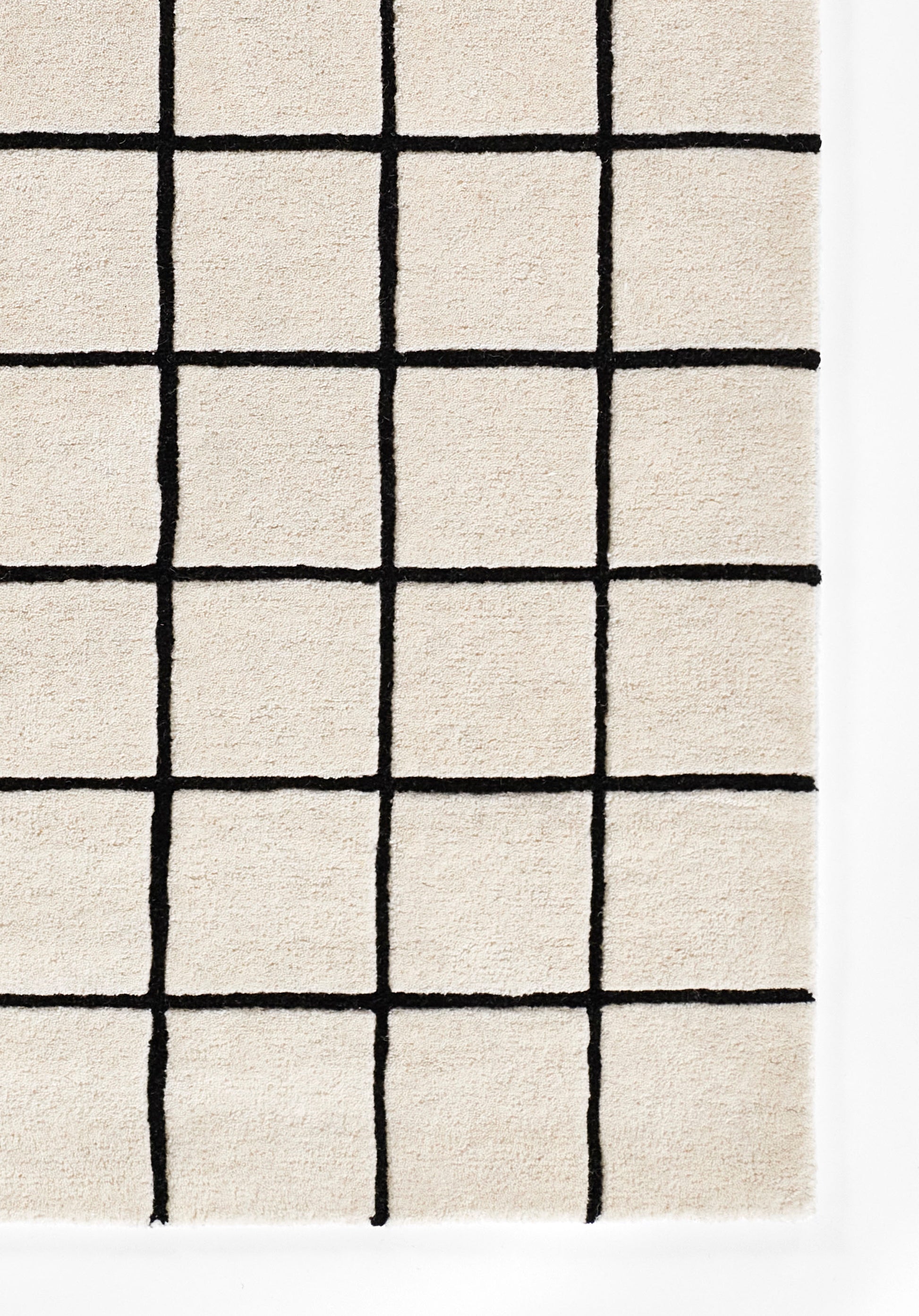 Beige rug with bold black grid pattern forming squares; soft woven texture for modern living spaces.