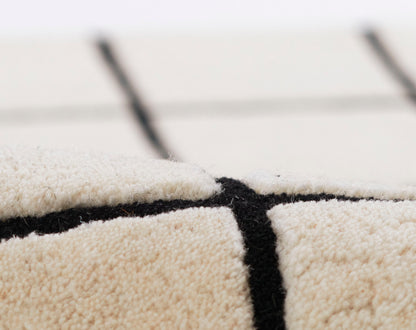 Close-up of cream beige rug with bold black grid lines and soft plush texture.