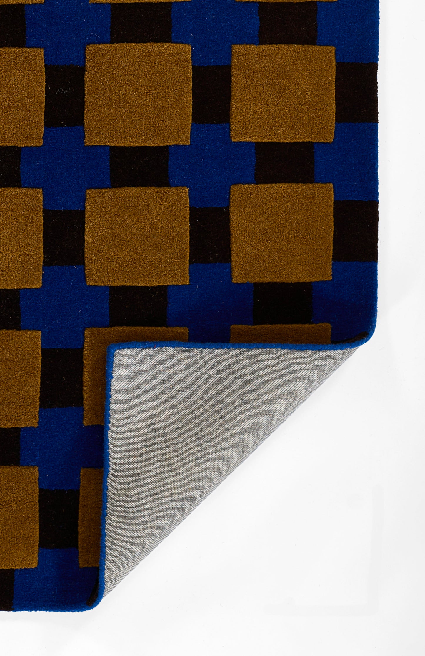 Geometric blue throw blanket with brown squares and black accents; folded to reveal grey underside and blue edge.