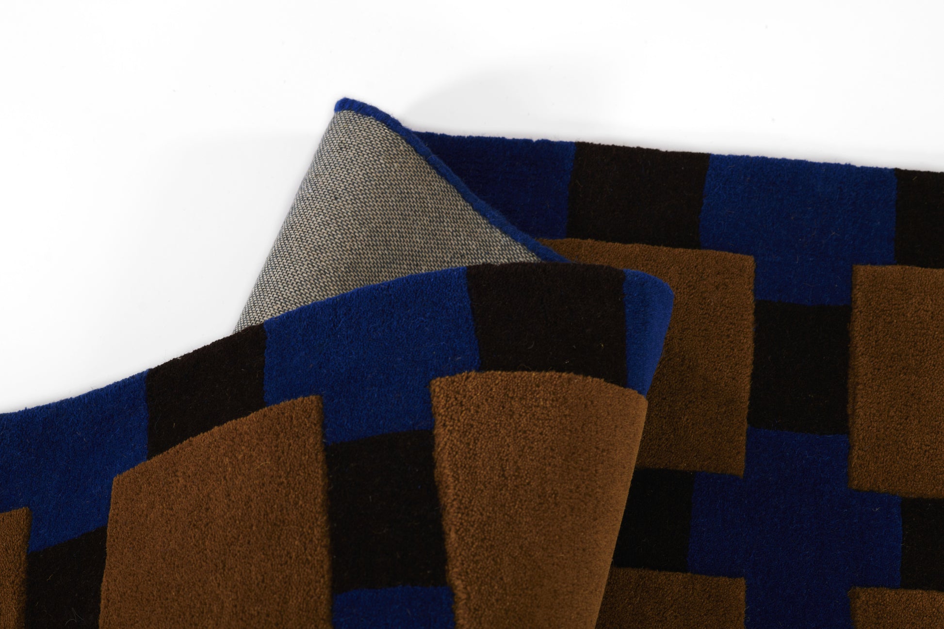 Geometric color-block scarf with blue, brown and black squares; woven wool fabric, folded.