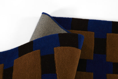 Geometric color-block scarf with blue, brown and black squares; woven wool fabric, folded.