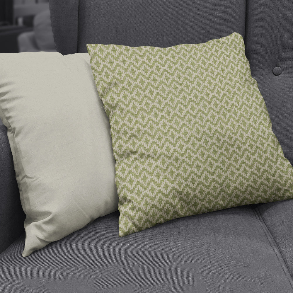 Two decorative cushions on a dark gray sofa: solid cream cushion & green geometric-patterned cushion.