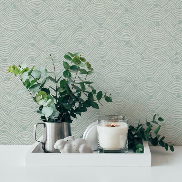 White tray centerpiece with a metal pitcher of eucalyptus, a white ceramic decor piece, and a glass candle holder.