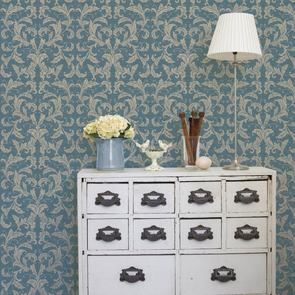 Vintage white dresser with 12 drawers, dark handles; blue damask wallpaper; lamp and blue pitcher with flowers.