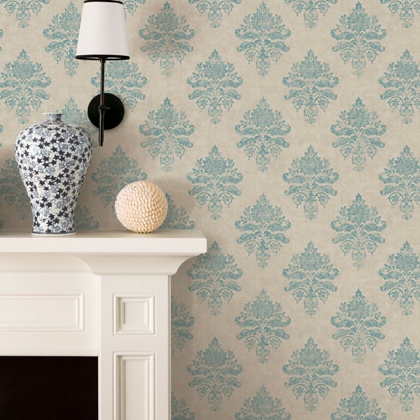 Blue damask wallpaper backdrop featuring a blue-and-white ceramic vase on a white mantel, a black wall lamp, and a cream textured sphere.