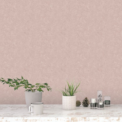 Soft pink marble-effect wallpaper above a whitewashed table with two potted plants, a white mug, pinecones, and glass jars.