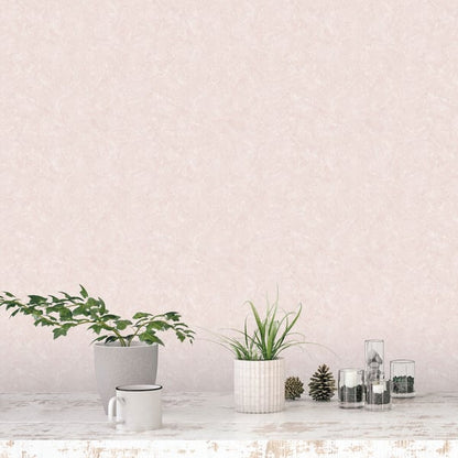 Soft pink wall, whitewashed table, two potted plants in gray ceramic and white ribbed pots, a mug, pinecones and glass jars.