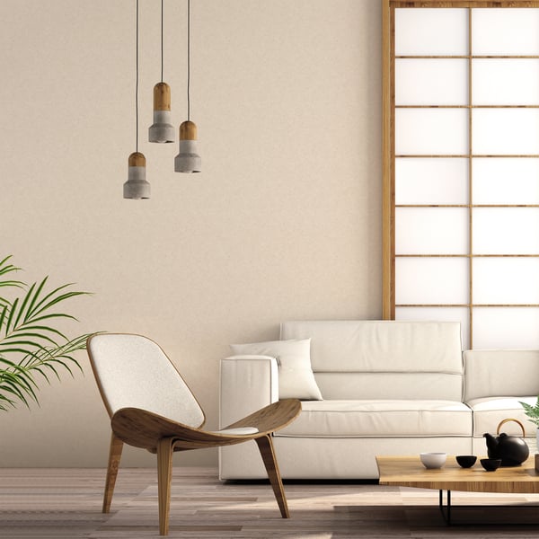 Neutral living room with bronze-brown small-print mini-texture wallpaper on walls, cream sofa, wooden lounge chair, pendant lights, coffee table, plant, and shoji screen.