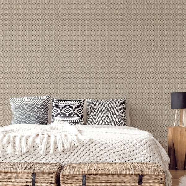 Boho bedroom: beige geometric wallpaper, cream chunky knit throw on bed & three gray/black patterned cushions.