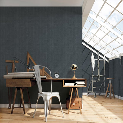 Industrial wooden desk with metal chair in a bright loft studio under skylight, clock and brass lamp on desk.