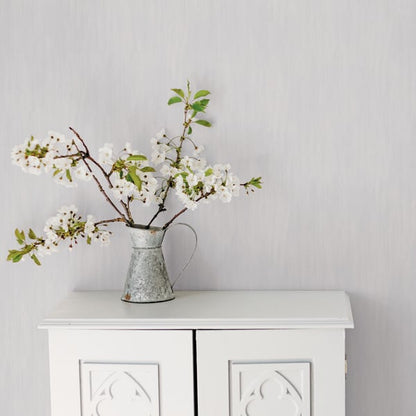 Floral wallpaper featuring white blossoms and green leaves on a soft silver-grey background with a wispy texture.