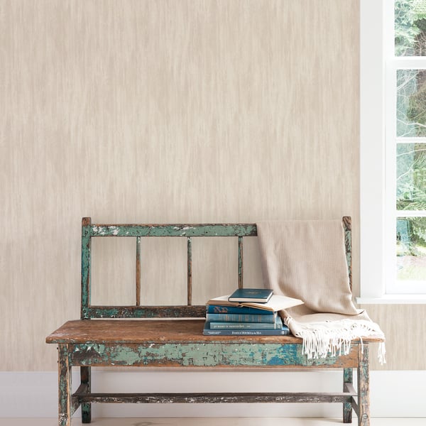Beige wallpaper with wispy texture on a sunlit wall.