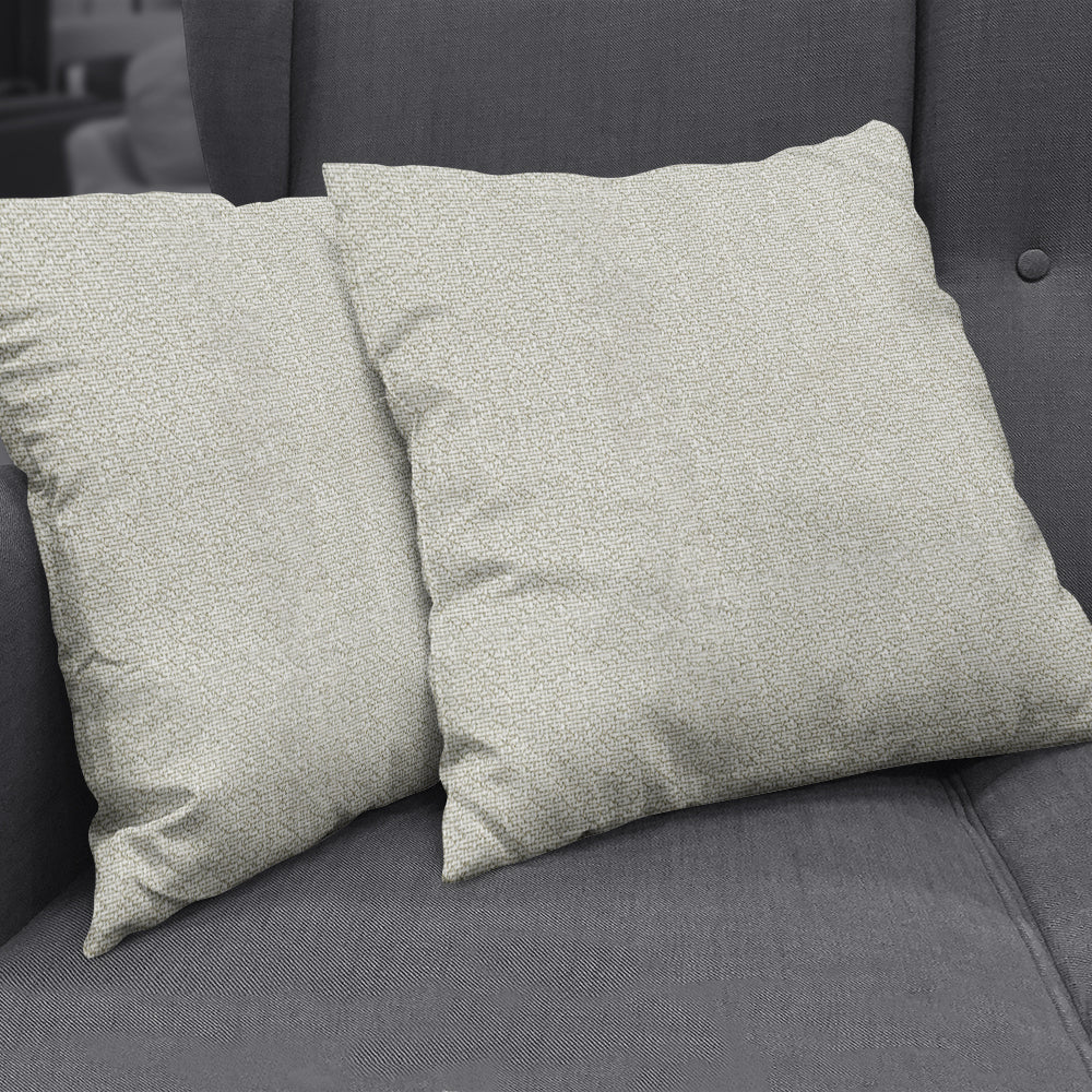 Beige textured square cushions on a dark gray sofa, decorative throw pillows.