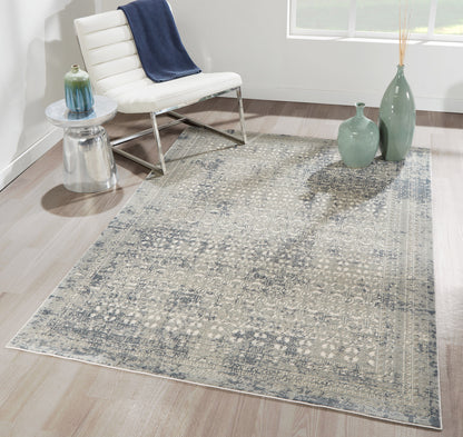 Blue-gray patterned area rug in a bright room with a white modern lounge chair, glass side table, and green ceramic vases.