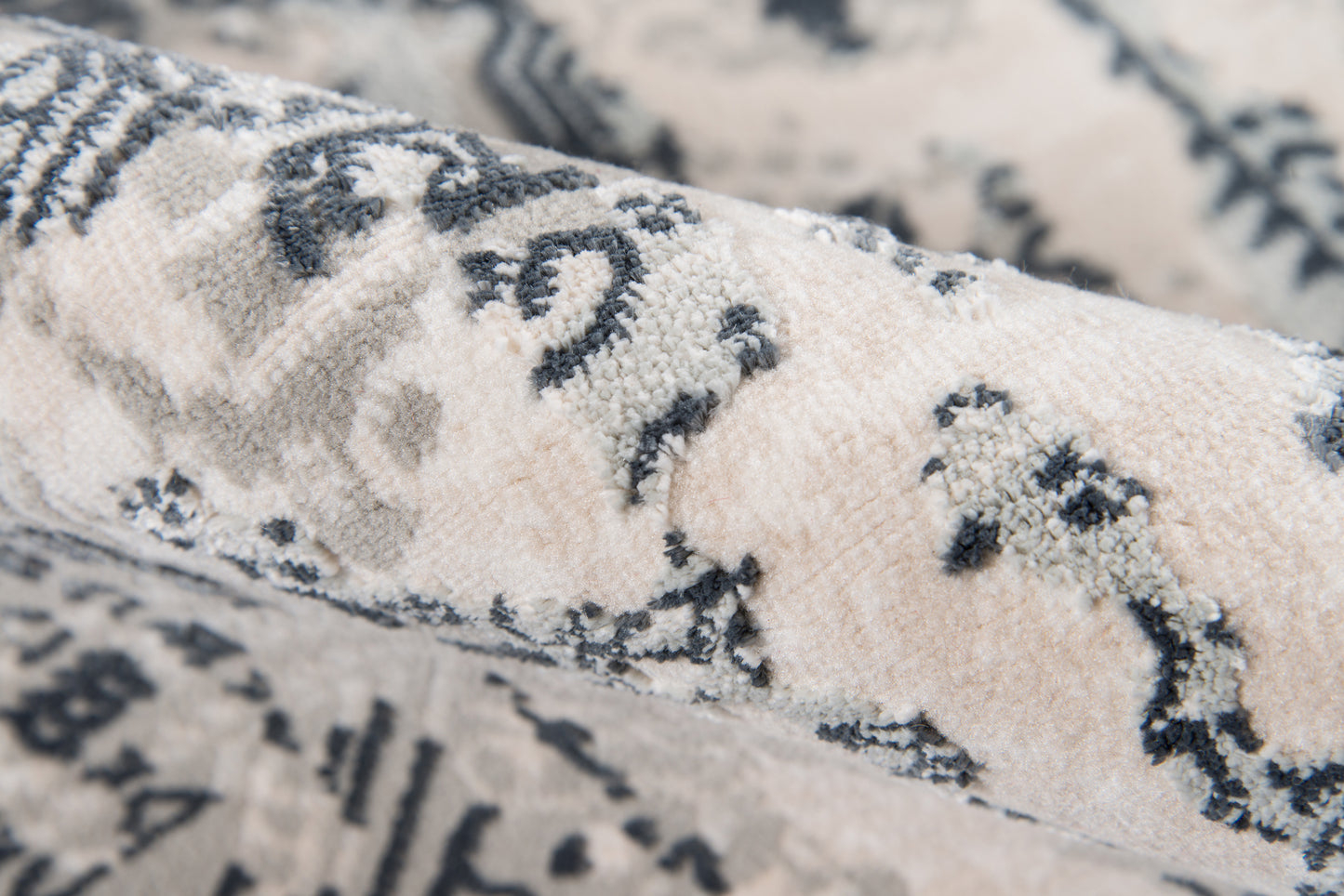 Close-up of cream and gray rug with soft plush pile and damask-inspired floral pattern.
