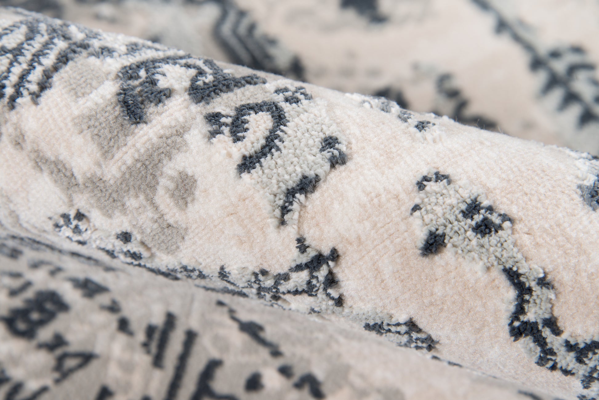 Close-up of cream and gray rug with soft plush pile and damask-inspired floral pattern.