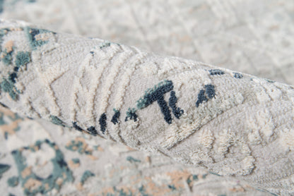 Close-up of a textured beige rug with blue-green accents and an abstract woven pattern.