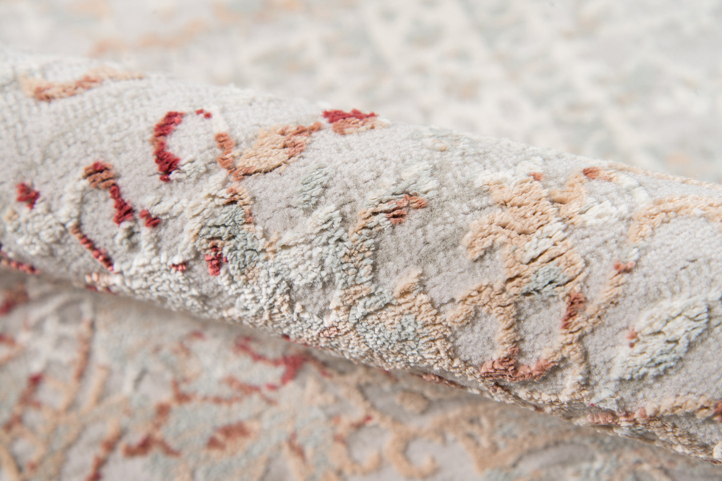 Close-up of a plush damask-pattern runner rug in cream-gray with peach and rust floral motifs.
