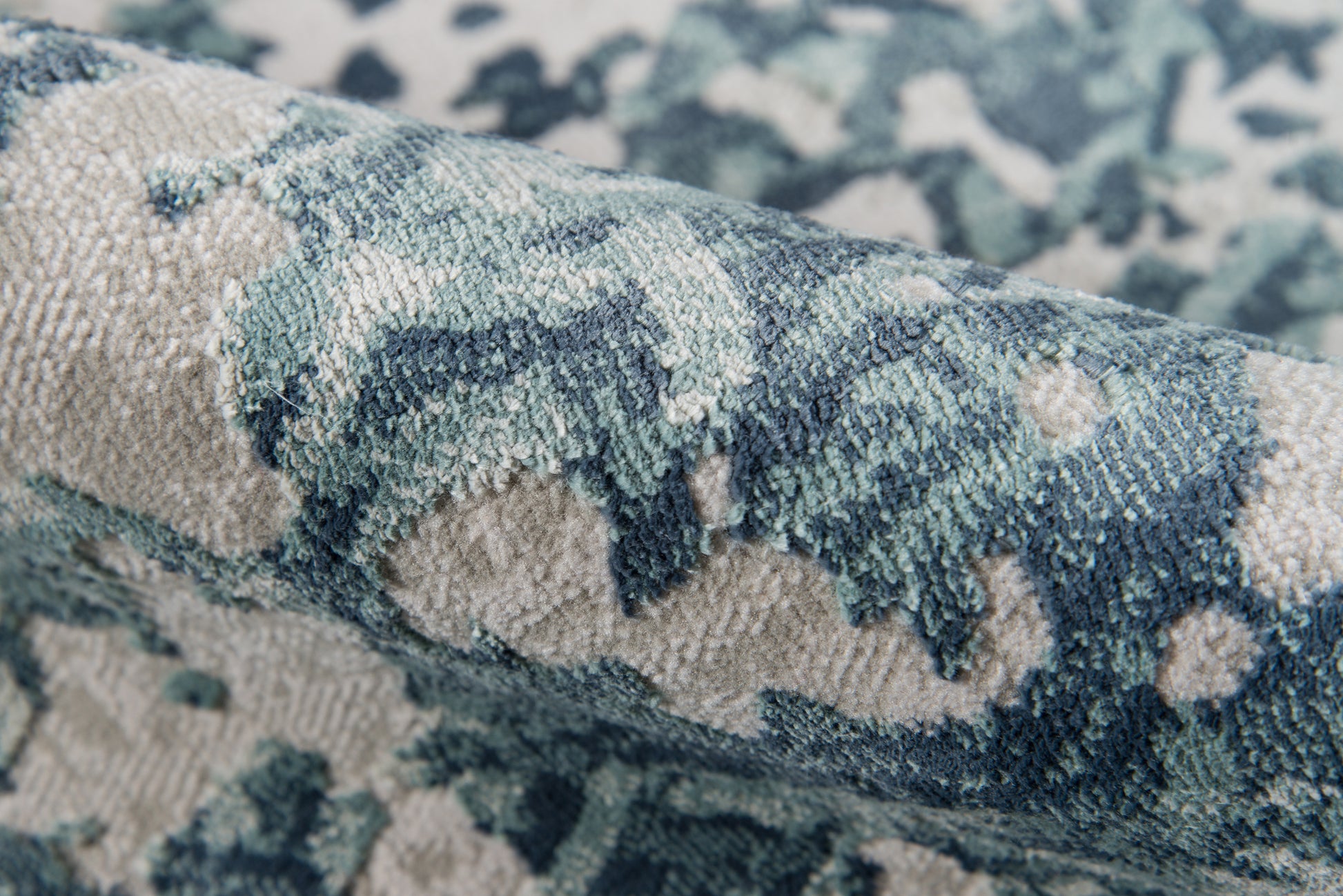 Close-up of blue and teal patterned runner with plush textured pile and beige backdrop.