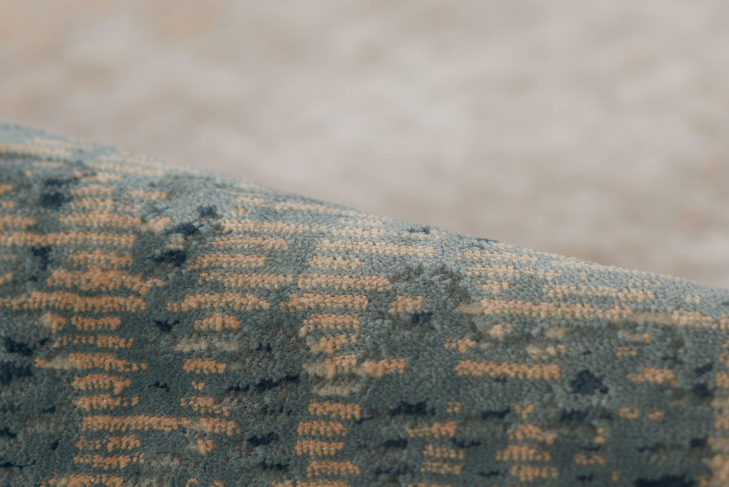 Close-up of blue velvet rug with a gold geometric weave.