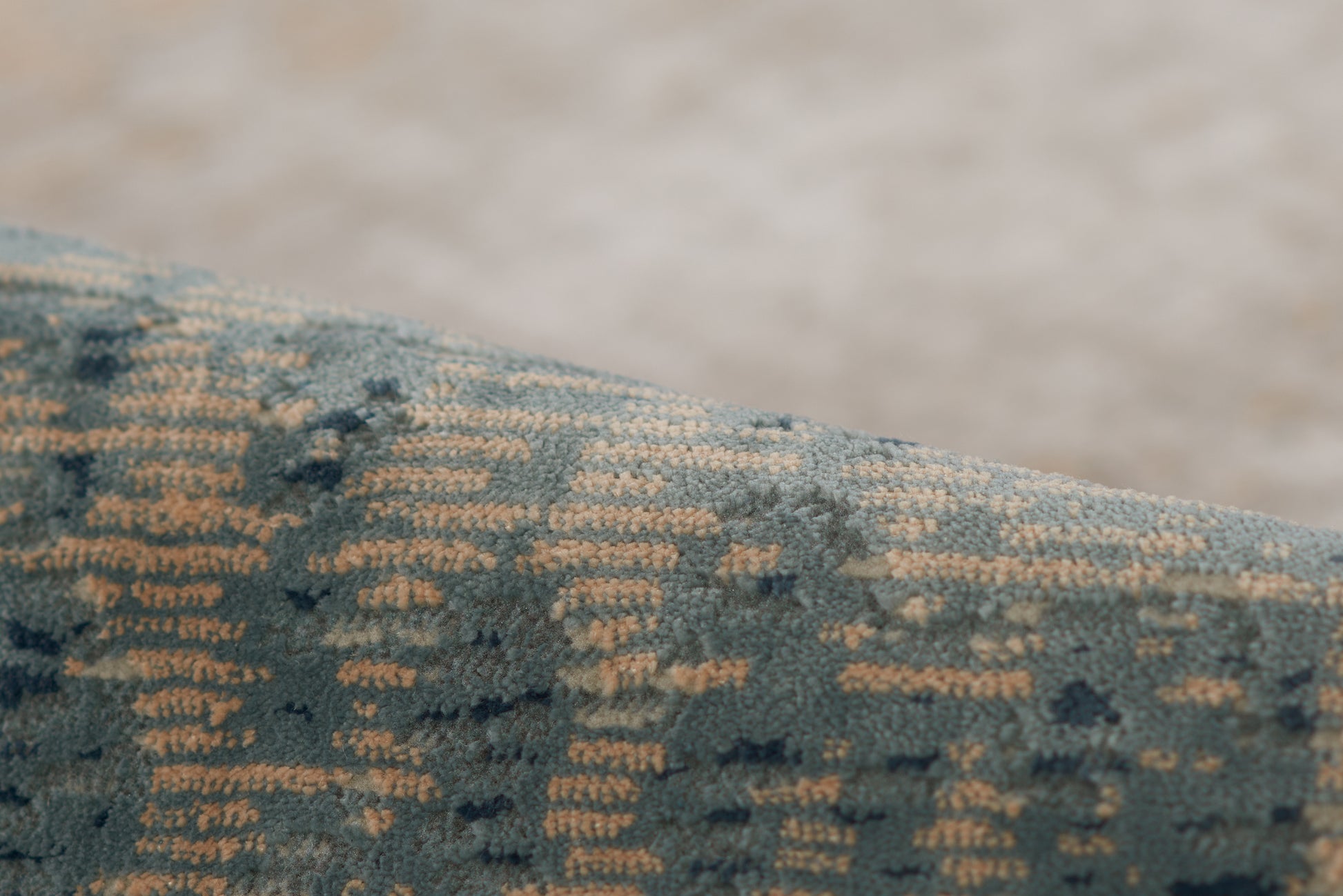 Close-up of blue velvet rug with a gold geometric weave.