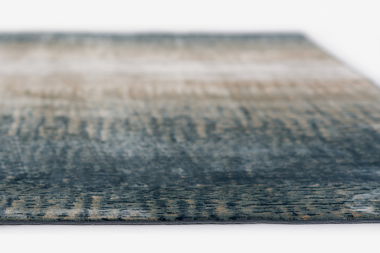 Blue gradient woven rug with beige accents; modern abstract area rug, close-up edge.