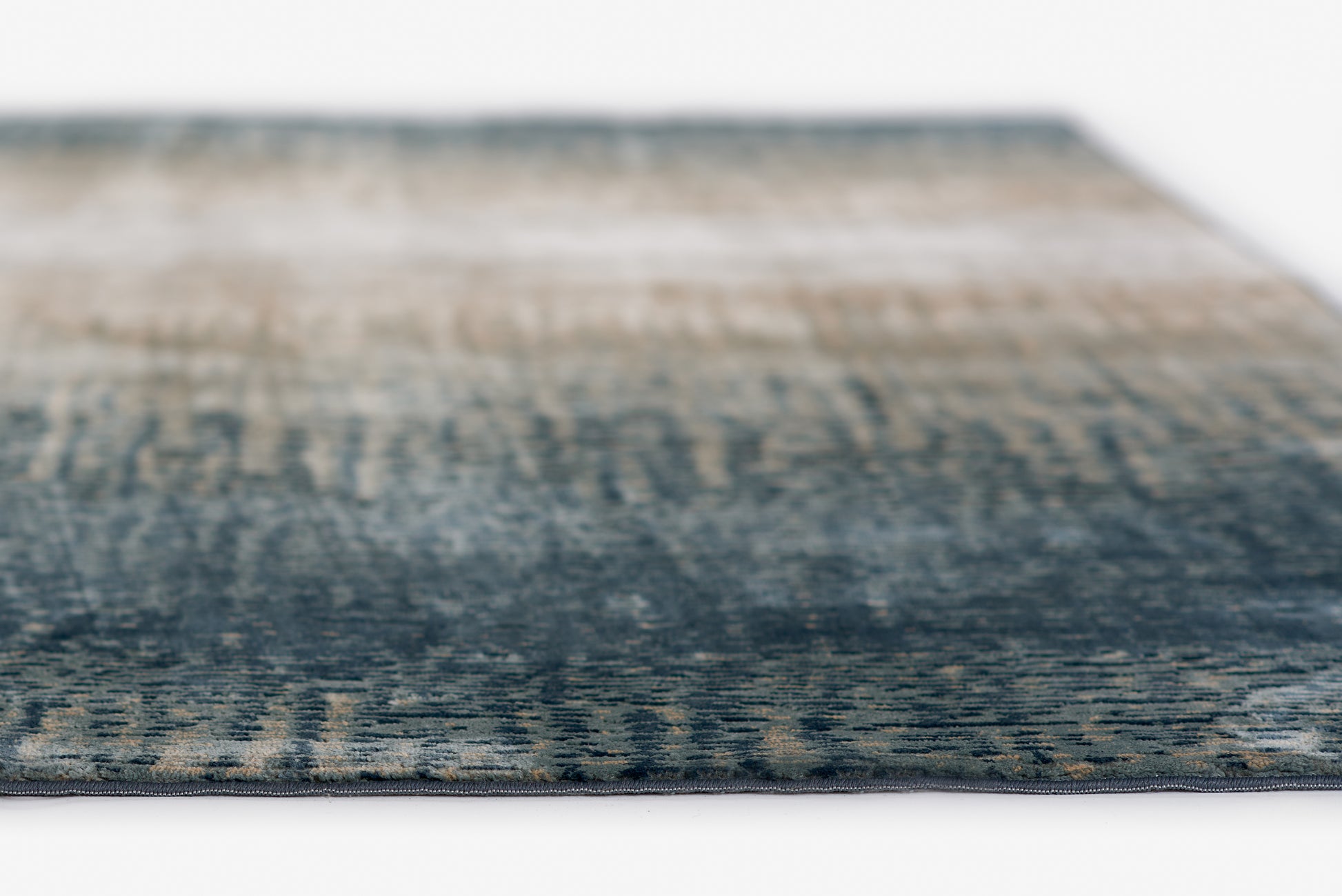 Blue gradient woven rug with beige accents; modern abstract area rug, close-up edge.