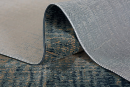 Light gray textured area rug with a rolled edge, exposing a blue patterned underside.