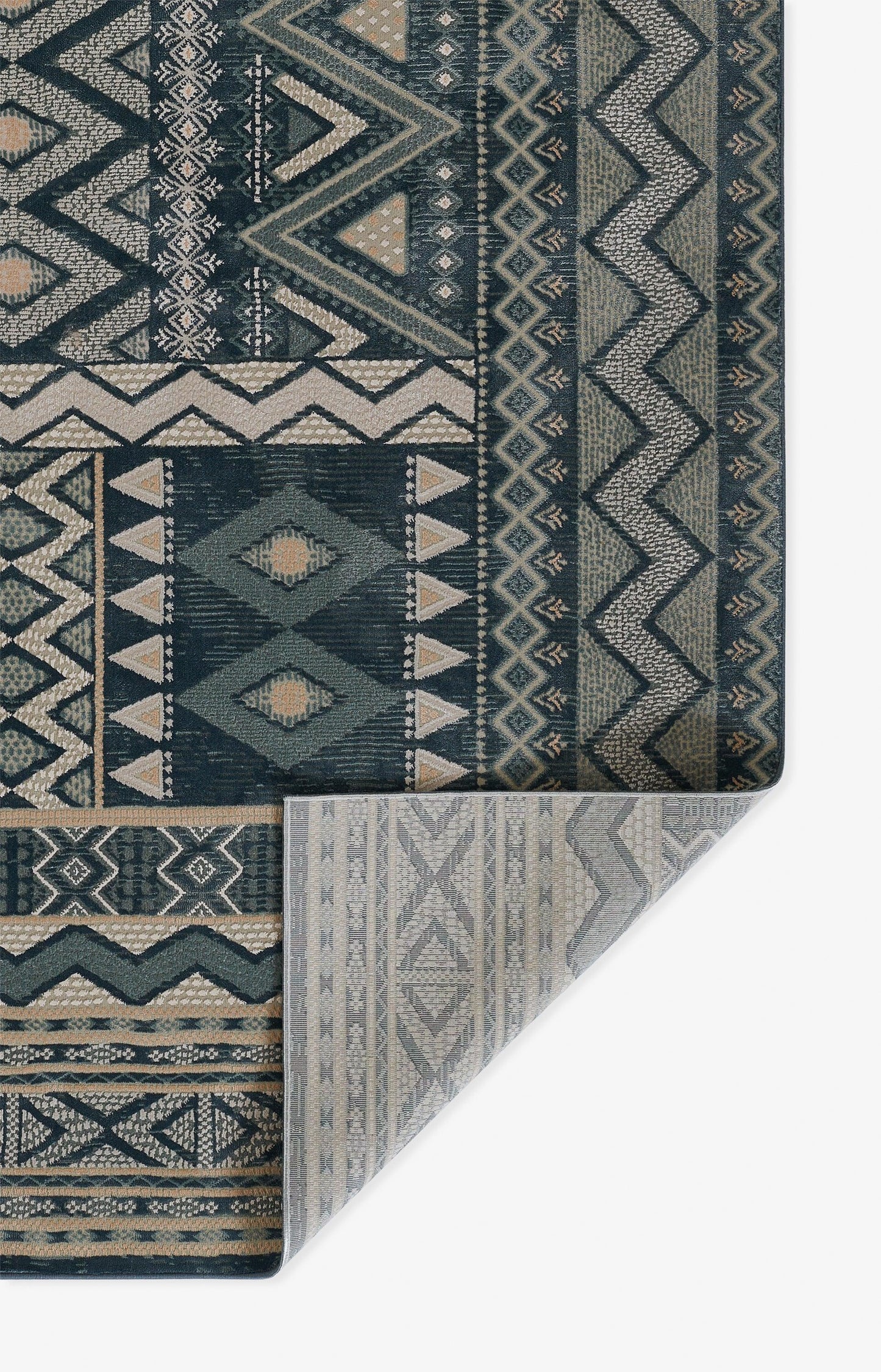 Blue and navy geometric rug with zigzag, diamonds, and tribal motifs; folded corner shows light gray underside