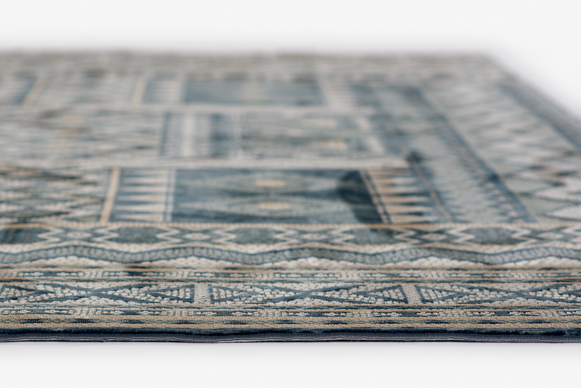 Blue and beige geometric rug, woven with traditional border pattern, close-up edge view.