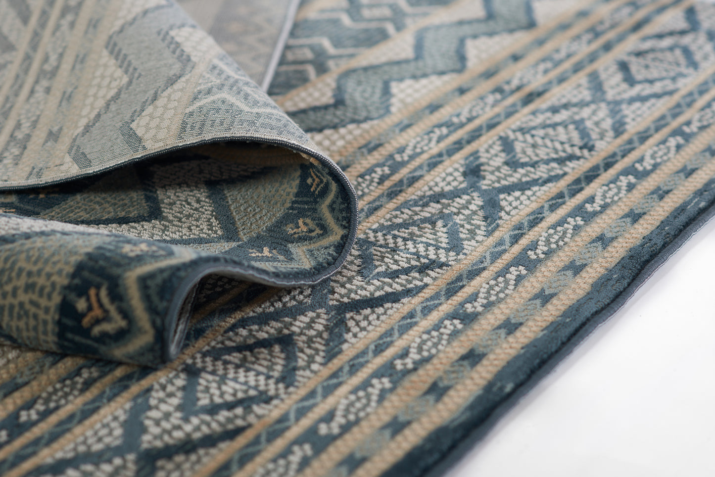 Blue & beige geometric woven rug with zigzag motif and decorative border, folded edge.