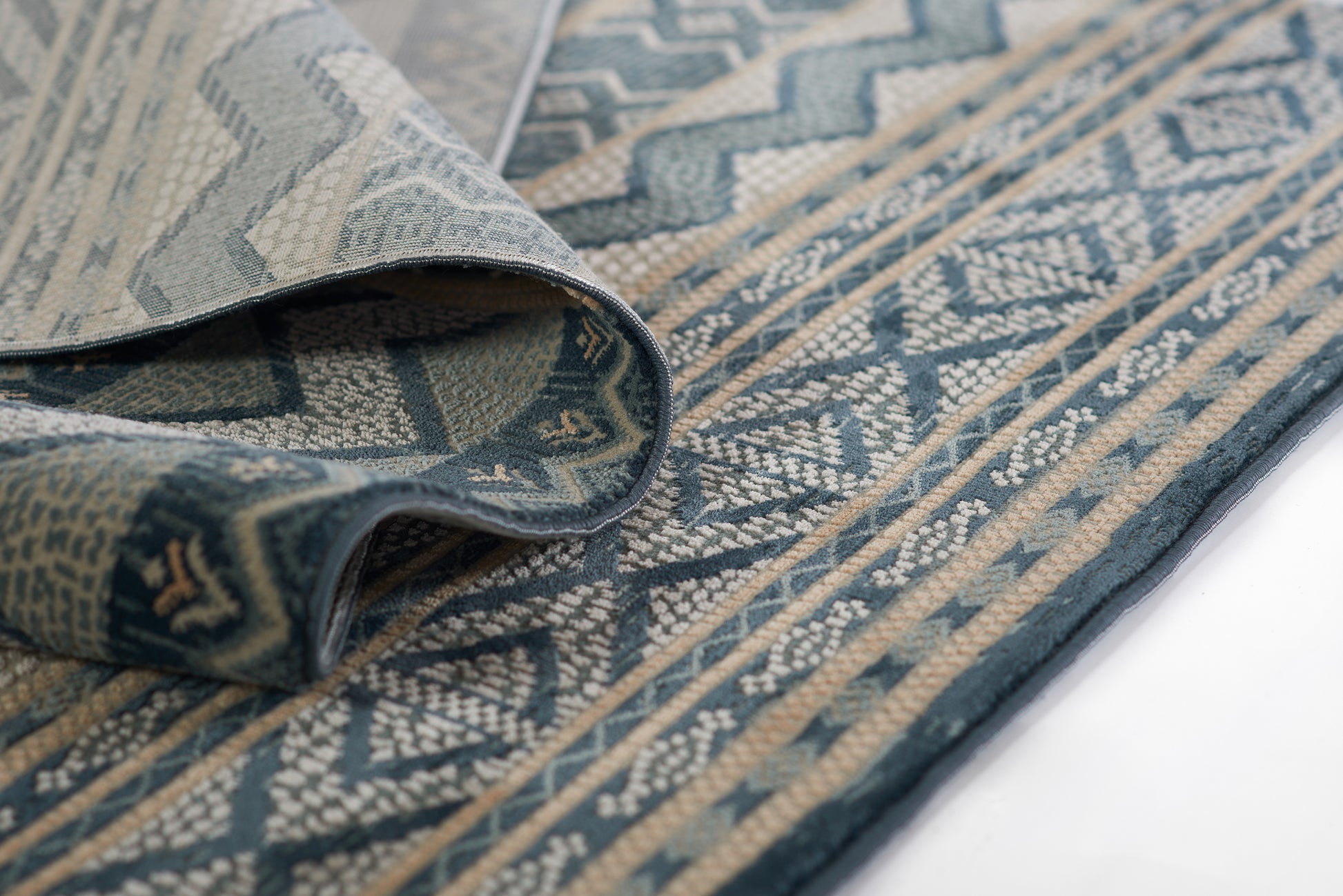 Blue & beige geometric woven rug with zigzag motif and decorative border, folded edge.