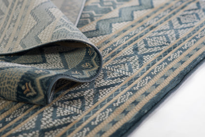 Blue & beige geometric woven rug with zigzag motif and decorative border, folded edge.