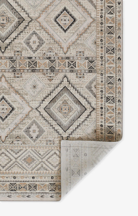 Neutral ivory-gray geometric rug with diamond medallions and borders; folded corner reveals the underside.